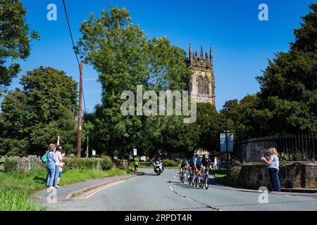 Szenen von Leg 2 der Tour of Britain, Wrexham bis Wrexham, während das Peleton eines der 7 Wonders of Wales, Gresfords All Saints Church, passiert. Stockfoto