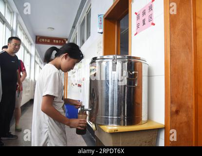 (190811) -- RIZHAO, 11. Aug. 2019 -- Ein Bürger (R) holt heißes Wasser an der provisorischen Umsiedlungsstelle in der Experimentellen Grundschule der Entwicklungszone Rizhao in Rizhao, ostchinesische Provinz Shandong, 11. Aug. 2019. Die Bürger werden in den provisorischen Einrichtungen umgesiedelt, bevor der Taifun Lekima, der neunte des Jahres, in einigen Gebieten der Stadt landete. ) CHINA-SHANDONG-RIZHAO-TYPHOON-LEKIMA (CN) WANGXKAI PUBLICATIONXNOTXINXCHN Stockfoto