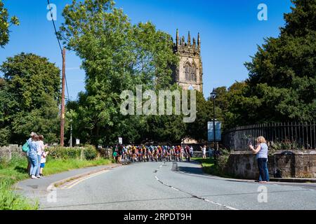 Szenen von Leg 2 der Tour of Britain, Wrexham bis Wrexham, während das Peleton eines der 7 Wonders of Wales, Gresfords All Saints Church, passiert. Stockfoto