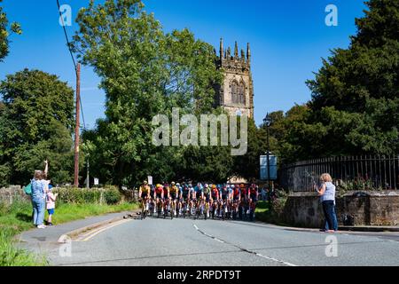 Szenen von Leg 2 der Tour of Britain, Wrexham bis Wrexham, während das Peleton eines der 7 Wonders of Wales, Gresfords All Saints Church, passiert. Stockfoto