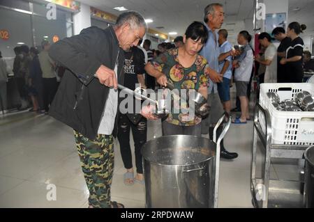 (190812) -- SHOUGUANG, 12. August 2019 -- Menschen essen in einer Mittelschule, die heute als Umzugsort dient, in Shouguang, Ostchinas Provinz Shandong, 12. August 2019. Etwa 93.000 Einwohner wurden umgesiedelt, da der Taifun Lekima in Teilen von Shouguang verheerende Schäden angerichtet hat. CHINA-SHANDONG-TYPHOON-LEKIMA-RELOCATION (CN) WANGXKAI PUBLICATIONXNOTXINXCHN Stockfoto