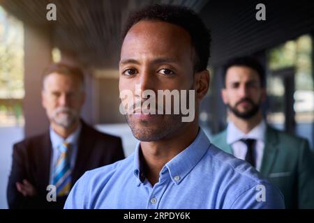 Seriöser amerikanischer Geschäftsmann in Anzügen, der sich vor dem Bürogebäude auf die Kamera konzentriert. Stockfoto