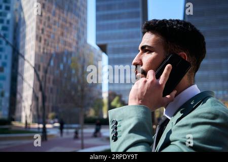 Seitenansicht junger gutaussehender kaukasischer Geschäftsmann, der mit dem Telefon spricht. Männlicher Profi. Stockfoto
