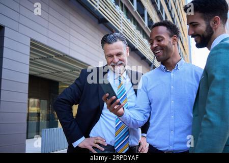 Afroamerikanischer Unternehmer zeigt Geschäftskollegen Ideen per Telefon. Erfolgreicher Büromitarbeiter. Stockfoto