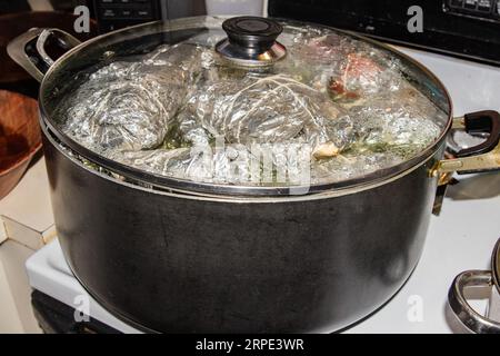 Fotografie von Topf auf kochenden Tamales in Silberfolie. Stockfoto