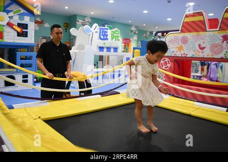 (190818) -- CHANGSHA, 18. August 2019 -- Xiao Yangbao beobachtet seine Tochter beim Springen auf dem Trampolin in einem Indoor-Spielplatz in Changsha, Hauptstadt der zentralchinesischen Provinz Hunan, 17. August 2019. Xiao Yangbao, ein 39-jähriger Arzt im Endoskopiezentrum des Hunan Chest Hospital, arbeitet seit fast 8 Jahren an der Prävention und Behandlung von Tuberkulose. Als Arzt, der endoskopische Operationen durchführt, ist Xiao einem höheren Risiko für Tuberkulose ausgesetzt und stellt höhere Anforderungen an die Präzision und Konzentration der Operation. Xiao fühlt sich jedes Mal befriedigt, wenn seine Patienten gesund wurden. Bis jetzt hat er Co Stockfoto