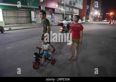 (190818) -- PEKING, 18. August 2019 -- Congcong und seine Eltern machen einen Spaziergang nach der Arbeit in Shishi, südöstliche chinesische Provinz Fujian, 5. August 2019. Die sengende Hitze hat Shishi im Südosten Chinas Fujian in diesem Sommer verschlingen lassen und nur wenige laufen auf den normalerweise geschäftigen Straßen. Im Gegensatz dazu sind die Kleiderfabriken, die in der Stadt dicht besiedelt sind, mit Menschen überfüllt, die von ihrer Arbeit überschwemmt wurden, da der Sommer die Hauptsaison für die Herstellung von Kleidungsstücken jedes Jahr ist, und auch ihre Kinder. Der Ruf Shishis als eines der wichtigsten Bekleidungshersteller im ganzen Land ist weitgehend attribu Stockfoto