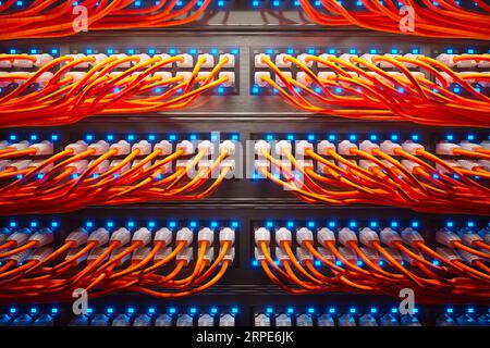 Unzählige orangefarbene Kabel in einem Metallgehäuse, das von einem einzigen Strahler beleuchtet wird. Stockfoto