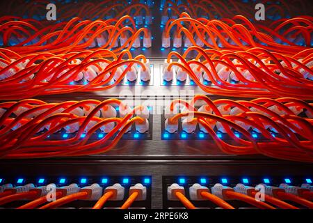 Unzählige orangefarbene Kabel in einem Metallgehäuse, das von einem einzigen Strahler beleuchtet wird. Stockfoto