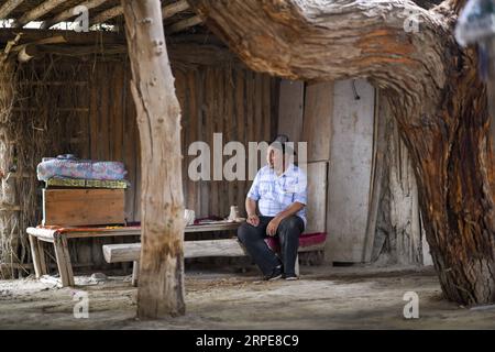 (190821) -- YULI, 21. August 2019 -- Amudun Abudu liegt zu Hause im Dorf Lop nur im Yuli County, nordwestchinesische Autonome Region Xinjiang Uygur, 21. Juni 2019. Lop nur People Village liegt im Yuli County, wo der Tarim River durch die Wüsten fließt, wobei die Populus euphratica Wälder die schimmernden Wellen reflektieren. Amudun Abudu, ein 61 Jahre alter typischer Dorfbewohner von Lop nur, arbeitet in der lokalen Tourismusbranche. Mit dem Wandel der Zeit haben viele Menschen in Lop nur verschiedene Lebensmöglichkeiten, doch er beharrt auf der Tradition des Fischens in Flüssen und Seen. Er macht nicht nur Deliciou Stockfoto