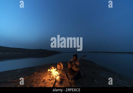 (190821) -- YULI, 21. August 2019 -- Amudun Abudu spielt ein Instrument in Lop nur People Village im Yuli County, nordwestchinesische Autonome Region Xinjiang Uygur, 11. April 2019. Lop nur People Village liegt im Yuli County, wo der Tarim River durch die Wüsten fließt, wobei die Populus euphratica Wälder die schimmernden Wellen reflektieren. Amudun Abudu, ein 61 Jahre alter typischer Dorfbewohner von Lop nur, arbeitet in der lokalen Tourismusbranche. Mit dem Wandel der Zeit haben viele Menschen in Lop nur verschiedene Lebensmöglichkeiten, doch er beharrt auf der Tradition des Fischens in Flüssen und Seen. Er macht nicht nur d Stockfoto