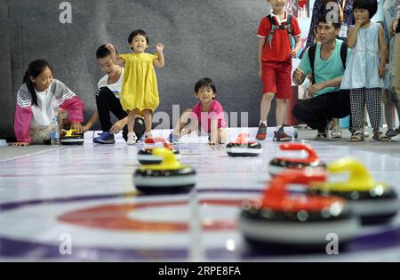 (190821) -- PEKING, 21. August 2019 -- Besucher versuchen das Spiel des Curling am Stand der Olympischen Winterspiele während der 26. Internationalen Buchmesse in Peking, Hauptstadt Chinas, 21. August 2019. Die Buchmesse und die 9. China Digital Publishing Expo begannen am Mittwoch am neuen Veranstaltungsort des China International Exhibition Center. ) CHINA-PEKING-BUCHMESSE (CN) JinxLiangkuai PUBLICATIONxNOTxINxCHN Stockfoto