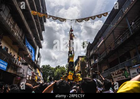 (190824) -- MUMBAI, 24. August 2019 -- Ein Mann steht auf einer menschlichen Pyramide, die von indischen Devotees gebildet wird, um einen Dahi-handi (Quark-Pot) während des Janmashtami Festivals in Mumbai, Indien, 24. August 2019 zu erreichen und zu brechen. Janmashtami ist ein jährliches Festival, das den Geburtstag von Hindu Lord Krishna feiert. (Foto: Fariha Farooqui/Xinhua) INDIA-MUMBAI-FESTIVAL-JANMASHTAMI XinxHuashe PUBLICATIONxNOTxINxCHN Stockfoto