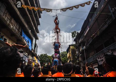 (190824) -- MUMBAI, 24. August 2019 -- Ein Mann steht auf einer menschlichen Pyramide, die von indischen Devotees gebildet wird, um einen Dahi-handi (Quark-Pot) während des Janmashtami Festivals in Mumbai, Indien, 24. August 2019 zu erreichen und zu brechen. Janmashtami ist ein jährliches Festival, das den Geburtstag von Hindu Lord Krishna feiert. (Foto: Fariha Farooqui/Xinhua) INDIA-MUMBAI-FESTIVAL-JANMASHTAMI XinxHuashe PUBLICATIONxNOTxINxCHN Stockfoto