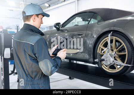 Servicemänner mit digitalem Tablet auf dem Hintergrund des Autos im Autodienst. Stockfoto