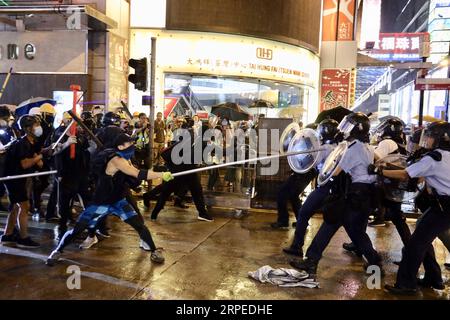 (190825) -- HONG KONG, 25. August 2019 -- radikale Demonstranten greifen Polizeibeamte in Tsuen Wan, in den westlichen Neuen Territorien des südchinesischen Hongkong, 25. August 2019 an. Radikale Demonstranten blockieren verschiedene Straßen, werfen Ziegel und Steine auf Polizeibeamte. Lui Siu Wai) CHINA-HONG KONG-PROTEST-VIOLENCE (CN) LyuxXiaowei PUBLICATIONxNOTxINxCHN Stockfoto