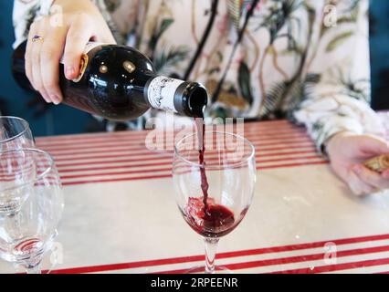 190827 -- PEKING, 27. August 2019 -- Ein Mitarbeiter gießt Wein für Gäste am Stand des Bordeaux-Weins im G7-Gipfelpressezentrum in Biarritz, Frankreich, am 26. August 2019. Xinhua-Schlagzeilen: G7-Gipfel endet mit dem transatlantischen Rift, der schwer zu verbergen ist. GaoxJing PUBLICATIONxNOTxINxCHN Stockfoto
