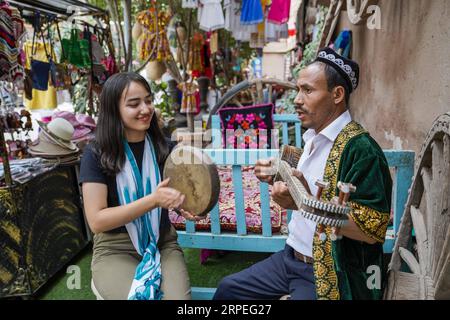 (190828) -- ÜRÜMQI, 28. August 2019 -- Anwohner, die in der Tourismusbranche tätig sind, spielen Musik für Touristen in der Altstadt von Kashgar, Nordwestchinas Autonome Region Xinjiang Uygur, 9. Juli 2019. Eine wachsende Zahl von Anwohnern verdient Geld aus dem aktuellen Tourismusboom in Xinjiang. Im ersten Halbjahr 2019 waren mehr als 32.000 Menschen in der Tourismusbranche beschäftigt. ) CHINA-XINJIANG-ECONOMY-TOURISM-EMPLOYMENT (CN) ZHAOXGE PUBLICATIONXNOTXINXCHN Stockfoto