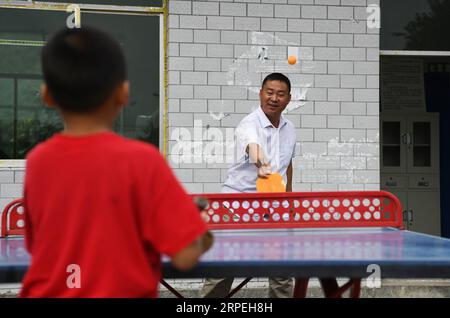 (190829) -- GUIYANG, 29. August 2019 -- Wu Guoxian spielt Tischtennis mit seinem Schüler während einer PE-Klasse an der Gugang Primary School im Dorf Liuguang im Kreis Longli in der autonomen Präfektur Qiannan, Provinz Guizhou im Südwesten Chinas, 27. August 2019. Die Gugang Primary School im Dorf Liuguang liegt tief in den Bergen und begrüßte sechs Vorschulkinder und vier Erstklässler, als das neue Semester am Montag begann. Sie werden von Wu Guoxian unterrichtet, dem einzigen Schullehrer hier. Wu, 53, arbeitet seit 36 Jahren an der Schule, seit er 198 an einer Junior High School abschloss Stockfoto