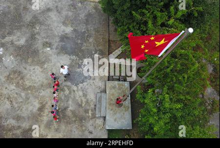 (190829) -- GUIYANG, 29. August 2019 -- Luftaufnahme am 27. August 2019 zeigt Wu Guoxian und Studenten, die an einer Flaggenhisserungszeremonie in der Gugang-Grundschule im Dorf Liuguang im Kreis Longli in der autonomen Präfektur Qiannan, Provinz Guizhou im Südwesten Chinas, teilnehmen. Die Gugang Primary School im Dorf Liuguang liegt tief in den Bergen und begrüßte sechs Vorschulkinder und vier Erstklässler, als das neue Semester am Montag begann. Sie werden von Wu Guoxian unterrichtet, dem einzigen Schullehrer hier. Wu, 53, arbeitet seit 36 Jahren an der Schule Stockfoto