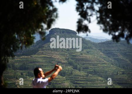 (190830) -- MENGYIN, 30. August 2019 -- Ein Tourist macht Fotos am landschaftlich reizvollen Ort Daigu in der ostchinesischen Provinz Shandong, 30. August 2019. Daigu, eine burgenförmige Landformation, ist eine Landform, die in den zentralen und südlichen Teilen der Provinz Shandong, insbesondere in der Region des Yimeng Mountain, einzigartig ist. Yimengshan Geopark erhielt 2019 das UNESCO Global Geopark Label. CHINA-SHANDONG-GEOPARK-DAIGU LANDFORM (CN) WANGXKAI PUBLICATIONXNOTXINXCHN Stockfoto