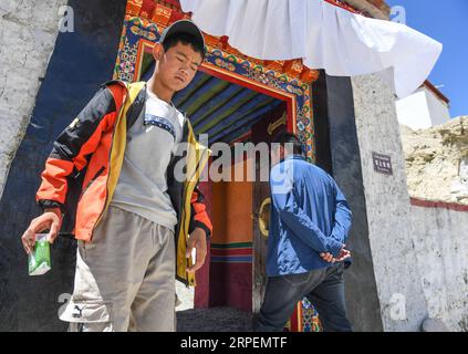 (190901) -- NGARI, 1. September 2019 (Xinhua) -- Basang Cering (R) passiert den Eingang der Reliquien des Königreichs Guge in der Präfektur Zanda, der autonomen Region Tibet im Südwesten Chinas, 30. Juli 2019. Jedes Jahr besuchen etwa 100.000 Menschen die Ruinen eines geheimnisvollen antiken Königreichs im Westen Tibets. Die meisten sind Touristen, die kurz durchfahren, aber nicht Basang Cering. Der 30-jährige Mann bewahrt seit 2013 die Reliquien des Königreichs Guge im Zanda County, Präfektur Ngari, der autonomen Region Tibet im Südwesten Chinas. Er studierte eine traditionelle tibetanische Maltechnik namens Thangka Stockfoto