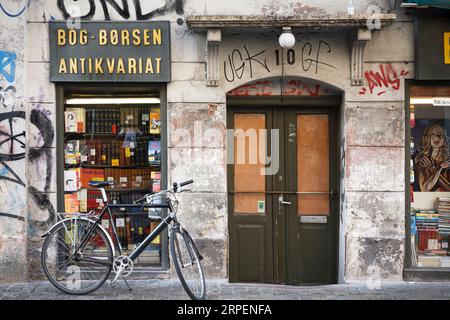 KOPENHAGEN, DÄNEMARK - 17. Juni 2006. Urban Grunge Street Szene, Fahrrad geparkt vor einer Ladentür mit Graffiti in Kopenhagen, Dänemark. Stockfoto