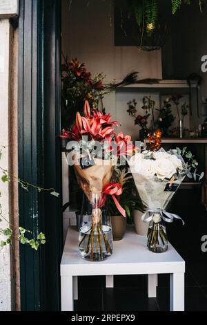 Verschiedene schöne Blumensträuße mit gemischten Blumen auf weißem Tisch am Eingang zum Laden, im Fenster. Blumengeschäft-Konzept. Leerzeichen kopieren Stockfoto