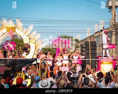 Barranquilla, Atlantico, Kolumbien - 18. Februar 2023: Männer und Frauen gekleidet in weiß und Pink auf einem Float in der Karnevalsparade, die der Menge zuwinkt Stockfoto