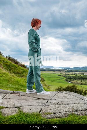 Frau, die in Fels steht, Dunadd Hill Fort, Kilmartin Glen, Argyll, Schottland, UK Stockfoto