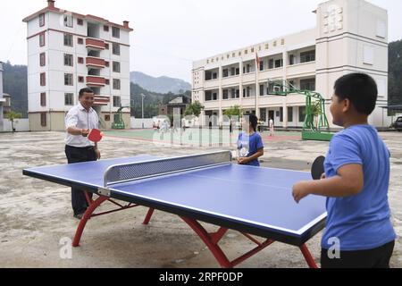 (190908) -- TIANDONG, 8. September 2019 -- Wei Guoji spielt Tischtennis mit Schülern der Tuogua Primary School im Dorf Tuogua im Zuodeng Yao Ethnic Township des Tiandong County, südchinesische Autonome Region Guangxi Zhuang, 3. September 2019. Die Grundschule Tuogua liegt in abgelegenen Bergen des Tiandong County und ist mehr als 60 km vom County Seat entfernt, zu dem nur eine schroffe Bergstraße führen kann. Der 53-jährige Wei Guoji, ein gebürtiger Bewohner des Dorfes, ist der Direktor der Dorfschule. Wei wurde als Ersatzlehrer der Schule nach dem Abschluss der Mittelschule im Alter von 18 Jahren rekrutiert Stockfoto