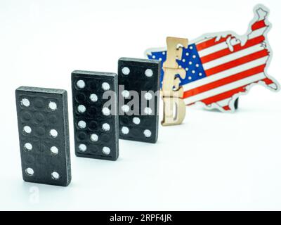 Ein Bild von drei schwarzen Domino-Fliesen mit den Buchstaben „FED“ in weiß, auf weißem Hintergrund mit der Flagge der Vereinigten Staaten im Hintergrund Stockfoto