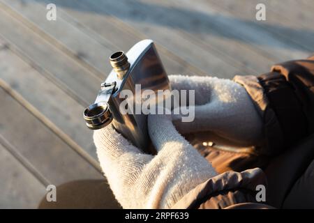 Glänzender Taschenkolben aus Stahl in den Händen, Außenfoto mit selektivem Fokus Stockfoto
