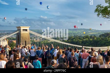 Zuschauer beobachten die Massenbesteigung von Heißluftballons bei der Bristol Balloon Fiesta im Himmel über der Clifton Suspension Bridge Stockfoto