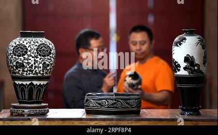 (190917) -- SHIJIAZHUANG, 17. September 2019 -- Liu Lizhong (L) tauscht sich mit seinem Sohn über die Schussfähigkeiten von Cizhou Kiln in einem Museum in der Stadt Handan, nordchinesische Provinz Hebei, 12. September 2019 aus. Liu Lizhong, 75, ist ein Erbe der Cizhou-Feuertechnik. Als vierte Generation in seiner Familie der Porzellanherstellung hat sich Liu der Erhaltung und Erforschung traditioneller Ofenbrennfähigkeiten verschrieben und hat erfolgreich die intakten 72 Verfahren der Cizhou-Ofenverbrennung geerbt. Nachdem er mehr als 100 Auszubildende rekrutiert hatte, sagte er, dass sein Traum darin bestehe, das traditionelle Handwerk an Jüngere weiterzugeben Stockfoto