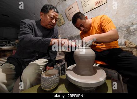 (190917) -- SHIJIAZHUANG, 17. September 2019 -- Liu Lizhong (L) führt seinen Sohn bei der Herstellung von Porzellan aus dem Cizhou-Ofen in einem Museum in der Stadt Handan, nordchinesische Provinz Hebei, 12. September 2019. Liu Lizhong, 75, ist ein Erbe der Cizhou-Feuertechnik. Als vierte Generation in seiner Familie der Porzellanherstellung hat sich Liu der Erhaltung und Erforschung traditioneller Ofenbrennfähigkeiten verschrieben und hat erfolgreich die intakten 72 Verfahren der Cizhou-Ofenverbrennung geerbt. Nachdem er mehr als 100 Auszubildende rekrutiert hatte, sagte er, dass sein Traum darin bestehe, das traditionelle Handwerk an jüngere Generationen weiterzugeben. Stockfoto