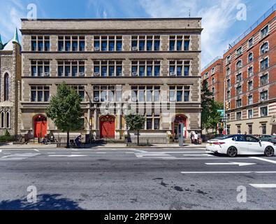 Upper West Side: School of the Holy Name of Jesus ist ein unsinniges, düsteres, graues Ziegel- und Steingebäude, das nur von bogenförmigen, rot bemalten Türen belebt wird. Stockfoto