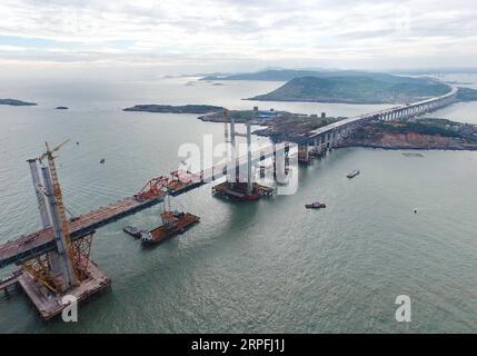 190925 -- FUZHOU, 25. September 2019 -- Luftaufnahme vom 21. September 2019 zeigt einen Stahlträger, der von einem Kran auf der Baustelle der Pingtan Strait Road-Rail Bridge in der südöstlichen chinesischen Provinz Fujian angehoben wird. Am Mittwoch vollendete China die Hauptstruktur der weltweit längsten überseeischen Straßen-Schiene-Brücke in Fujian. Der letzte Stahlträger mit einem Gewicht von 473 Tonnen wurde am Mittwochmorgen auf der Pingtan Strait Road-Rail Bridge, einem weiteren Megaprojekt in China, verschraubt. Mit einer atemberaubenden Spannweite von 16,34 km verbindet die Brücke die Insel Pingtan und vier nahe gelegene Inseln mit dem Festland von Fujian Pro Stockfoto