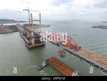 190925 -- FUZHOU, 25. September 2019 -- Luftaufnahme vom 21. September 2019 zeigt einen Stahlträger, der von einem Kran auf der Baustelle der Pingtan Strait Road-Rail Bridge in der südöstlichen chinesischen Provinz Fujian angehoben wird. Am Mittwoch vollendete China die Hauptstruktur der weltweit längsten überseeischen Straßen-Schiene-Brücke in Fujian. Der letzte Stahlträger mit einem Gewicht von 473 Tonnen wurde am Mittwochmorgen auf der Pingtan Strait Road-Rail Bridge, einem weiteren Megaprojekt in China, verschraubt. Mit einer atemberaubenden Spannweite von 16,34 km verbindet die Brücke die Insel Pingtan und vier nahe gelegene Inseln mit dem Festland von Fujian Pro Stockfoto