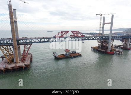 190925 -- FUZHOU, 25. September 2019 -- Luftaufnahme vom 21. September 2019 zeigt einen Stahlträger, der von einem Kran auf der Baustelle der Pingtan Strait Road-Rail Bridge in der südöstlichen chinesischen Provinz Fujian angehoben wird. Am Mittwoch vollendete China die Hauptstruktur der weltweit längsten überseeischen Straßen-Schiene-Brücke in Fujian. Der letzte Stahlträger mit einem Gewicht von 473 Tonnen wurde am Mittwochmorgen auf der Pingtan Strait Road-Rail Bridge, einem weiteren Megaprojekt in China, verschraubt. Mit einer atemberaubenden Spannweite von 16,34 km verbindet die Brücke die Insel Pingtan und vier nahe gelegene Inseln mit dem Festland von Fujian Pro Stockfoto