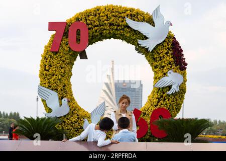 190930 -- DAQING, 30. September 2019 -- Eine Mutter und ihre Kinder posieren für ein Gruppenfoto auf dem Iron man Square in Daqing, nordöstliche Provinz Heilongjiang, 28. September 2019. Daqing Oilfield, entdeckt am 26. September 1959, ist das größte Ölfeld, das von PetroChina betrieben wird und auch die größte Ölförderbasis des Landes ist. Das Ölfeld, auf das einst mehr als die Hälfte der gesamten Rohölproduktion Chinas entfiel, hatte eine jährliche Rohölproduktion von über 50 Millionen Tonnen in 27 aufeinanderfolgenden Jahren und von über 40 Millionen Tonnen in 12 aufeinanderfolgenden Jahren. Die jährliche Erdöl- und Erdgasproduktion liegt nach wie vor bei über 40 Millionen Tonnen Stockfoto