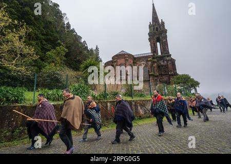 Römisch-katholische Pilger, genannt Romeiros, spazieren vorbei an der Kapelle unserer Lieben Frau von Siegen in Nebel und Regen während ihrer 8-tägigen Wanderung um die Azoren-Insel Sao Miguel, 30. März 2023 in Furnãs, Portugal. Die Pilger besuchen 100 Schreine und Kirchen während der Veranstaltung aus dem Jahr 1522, als ein Erdbeben die ersten Siedlungen zerstörte. Stockfoto