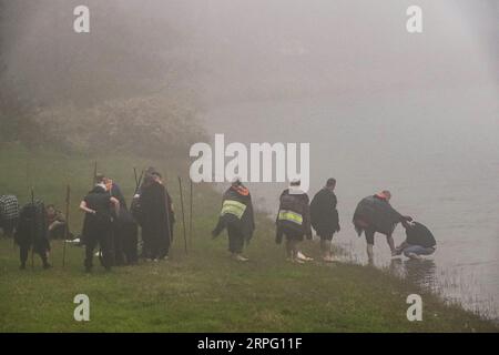 Ein römisch-katholischer Priester wäscht die Füße von Pilgern, die als Romeiros bekannt sind, in dichtem Nebel am Ufer des Furnas-Sees, 30. März 2023 in Lagoa das Furnãs, Portugal. Die Pilger besuchen 100 Schreine und Kirchen während ihrer 8-tägigen Wanderung um die Azoreninsel Sao Miguel, die aus dem Jahr 1522 stammt, als ein Erdbeben die ersten Siedlungen zerstörte. Stockfoto