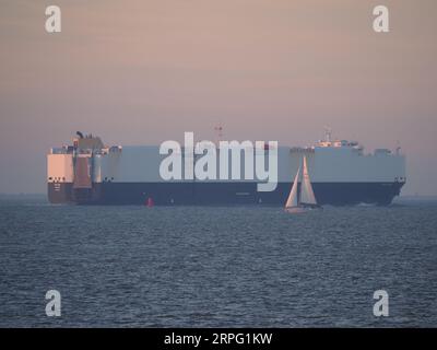 Sheerness, Kent, Großbritannien. September 2023. Wetter in Großbritannien: Sonnenuntergang in Sheerness, Kent am Ende eines warmen Tages. Eine Yacht passiert den Fahrzeugträger Patara. Quelle: James Bell/Alamy Live News Stockfoto