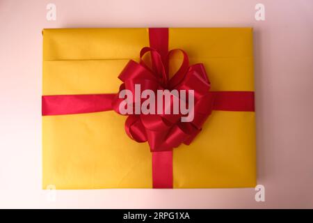Gelb verpackte Geschenkbox mit rotem Band Stockfoto