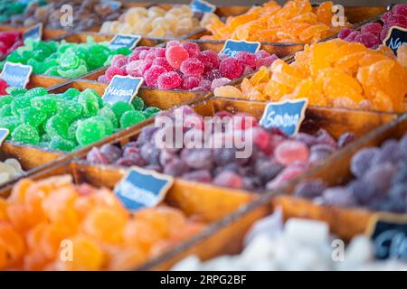 Süße Süßigkeiten in verschiedenen Farben und Texturen, im Vordergrund, mit Zucker auf der Oberseite und auf einem rustikalen Holzbehälter Stockfoto