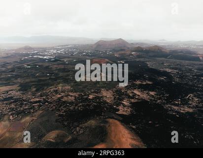 Luftbild von Vulkanen auf Lanzarote - Kanarische Inseln. Foto von vulkanischen dunklen Bergen und Kratern aus großer Höhe mit Drohne. Wunderschöne Landschaft Stockfoto