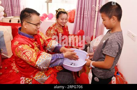 191005 -- TONGREN, 5. Oktober 2019 -- Bräutigam Pan Rongdong und Braut Tan Lifei waschen sich die Hände, um an ihrem Hochzeitstag in ihrem Haus im Bezirk Bijiang der Stadt Tongren, Provinz Guizhou im Südwesten Chinas, am 4. Oktober 2019 für Glück zu beten. Pan Rongdong ist ein Mitarbeiter des Gesundheitszentrums für Mütter und Kinder im Bezirk Wanshan in Tongren. Im September 2017, als Pan in das Dorf Wengbei in der Gemeinde Aozhai in Wanshan geschickt wurde, um an der Armutsbekämpfung zu arbeiten, lernte er Tan Lifei kennen, den Direktor der Armutsbekämpfungsstation für Aozhai. Während ihrer Arbeit an gezielten p Stockfoto