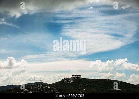 Eine kleine Hütte auf einem Hügel mit bewölktem Himmel. Stockfoto