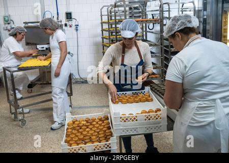 Bäckerinnen bereiten Queijadas, ein traditionelles Pudding-Gebäck, in der Queijadas do Morgado Bäckerei und im Café in Vila Franca do Campo auf der Insel Sao Miguel auf den Azoren, Portugal zu. Die Kuchen wurden im 16. Jahrhundert von Nonnen kreiert und als Queijadas de Vila Franca bezeichnet. Stockfoto